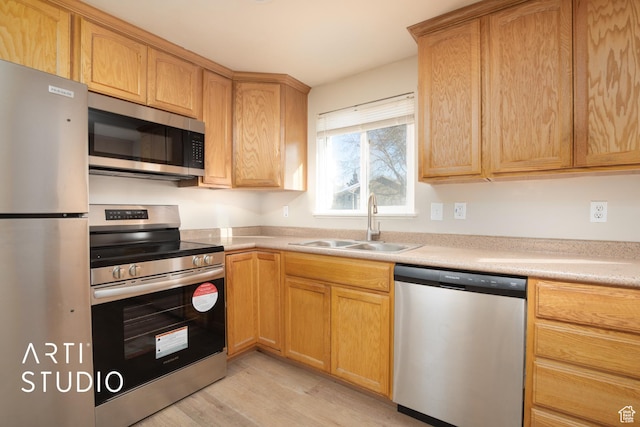 kitchen featuring light countertops, appliances with stainless steel finishes, light wood-style flooring, and a sink