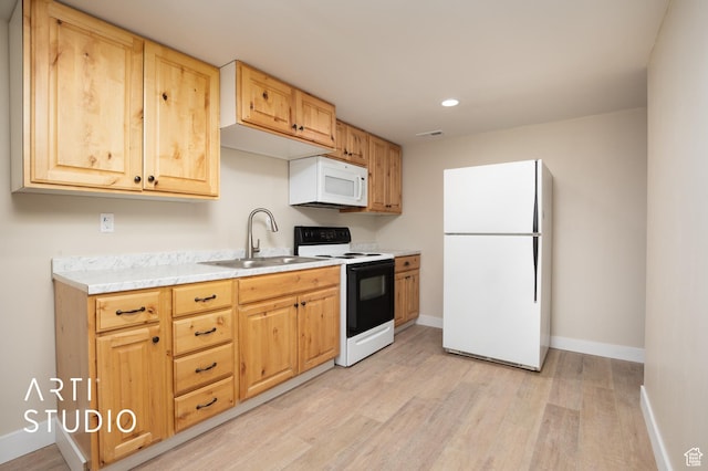 kitchen with a sink, white appliances, light wood finished floors, light countertops, and baseboards