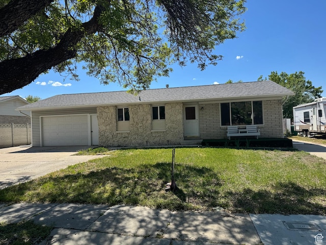ranch-style home with an attached garage, a front lawn, driveway, and stone siding