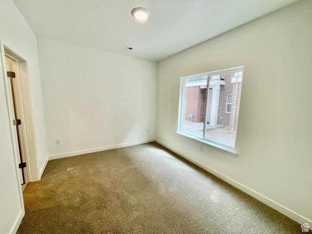 carpeted spare room featuring baseboards