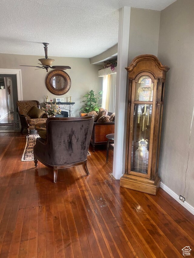 living area featuring a textured ceiling, wood-type flooring, and a ceiling fan