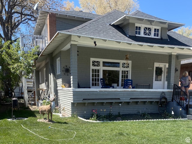 exterior space featuring a lawn, a porch, and a shingled roof