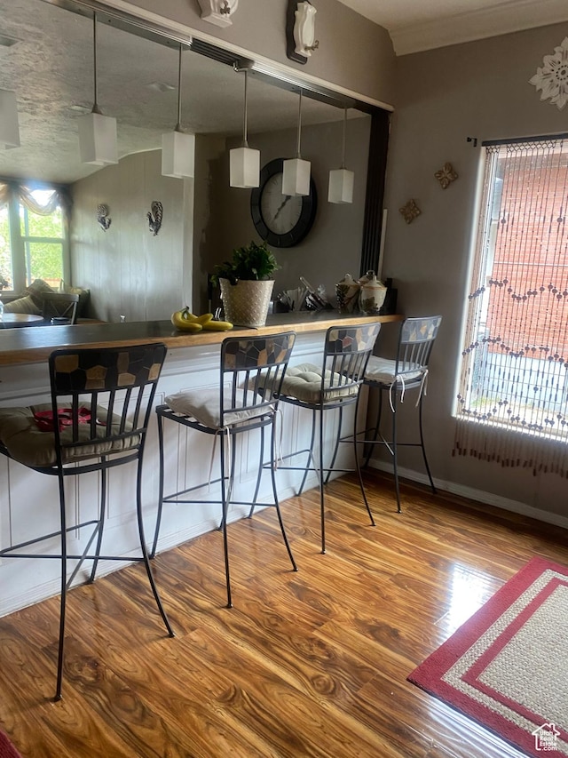 kitchen with a breakfast bar area, wood finished floors, and baseboards