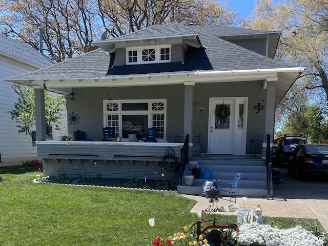 bungalow-style home with covered porch, roof with shingles, and a front lawn