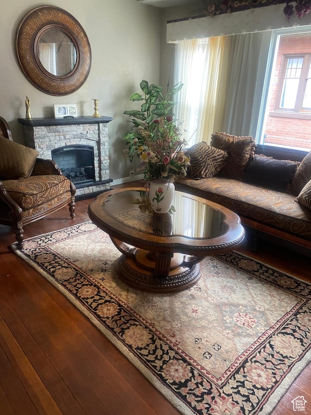 living area featuring hardwood / wood-style floors and a stone fireplace