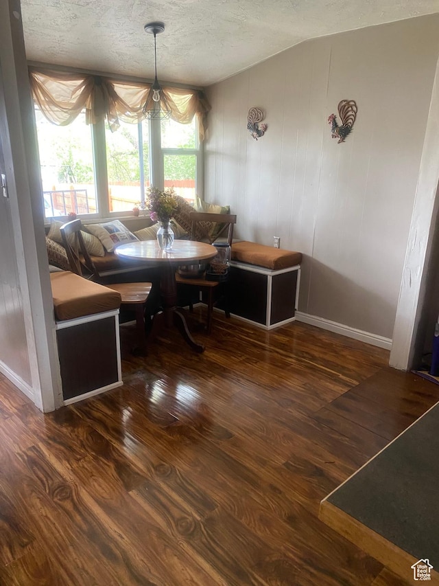 dining room with a textured ceiling, baseboards, and wood finished floors