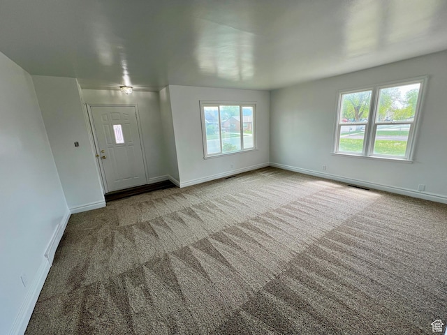 foyer entrance featuring carpet flooring, baseboards, and visible vents
