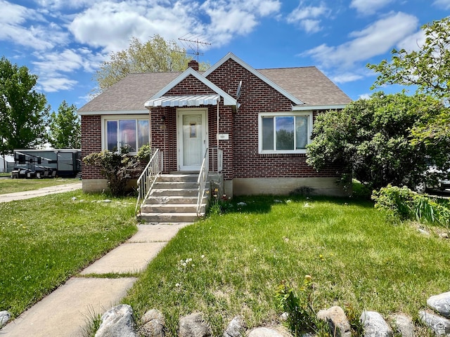 view of front of house with a front lawn, brick siding, roof with shingles, and a chimney