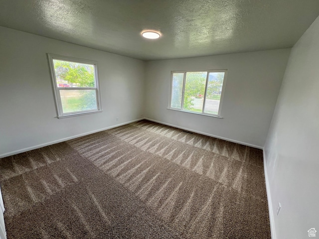 carpeted empty room with baseboards and a textured ceiling