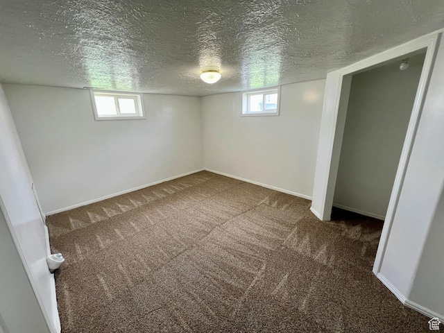 below grade area featuring carpet flooring, a textured ceiling, and baseboards