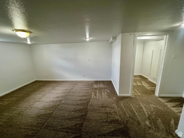 below grade area featuring a textured ceiling, carpet, and baseboards