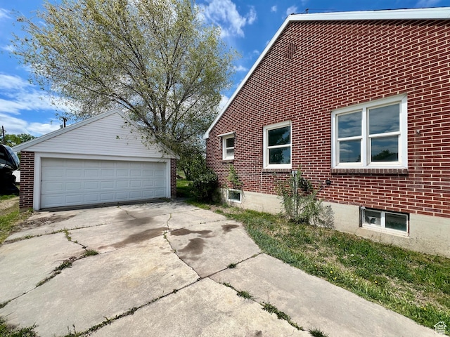 view of side of property with an outdoor structure, brick siding, and a garage