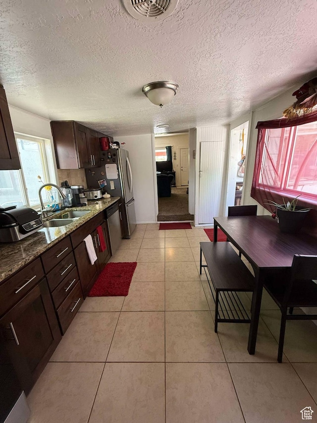 3274 W 3100 S, West Valley City, UT 84119 - kitchen featuring light tile patterned floors, dark brown cabinets, a sink, a textured ceiling, and stainless steel dishwasher