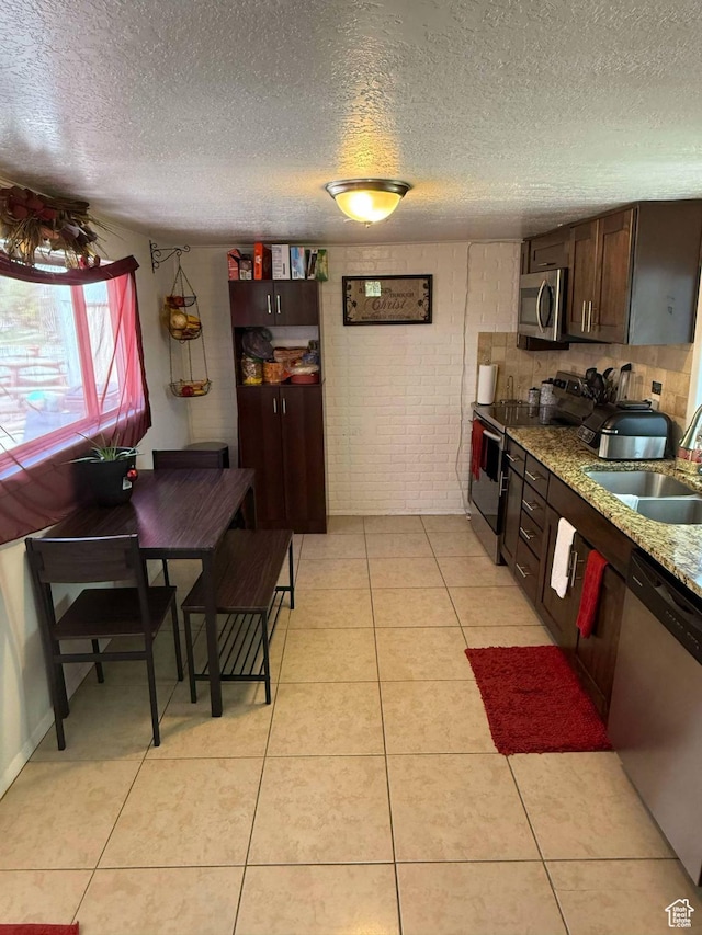 3274 W 3100 S, West Valley City, UT 84119 - kitchen featuring a sink, stainless steel appliances, a textured ceiling, dark brown cabinetry, and brick wall