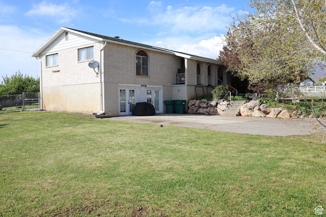 rear view of house with fence, french doors, and a lawn