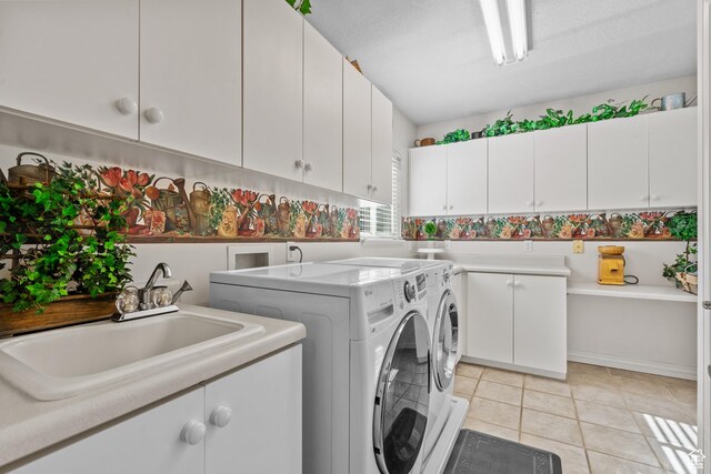 laundry room with light tile patterned floors, a sink, cabinet space, and washer and clothes dryer