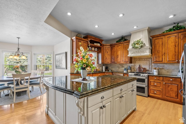 kitchen featuring stainless steel appliances, light wood-type flooring, custom range hood, and a kitchen island