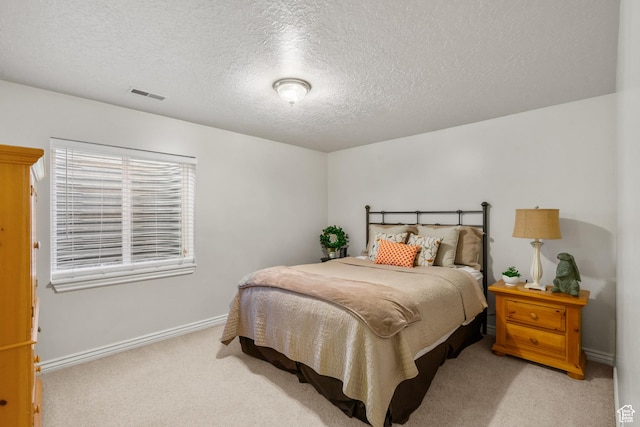 carpeted bedroom featuring a textured ceiling, baseboards, and visible vents