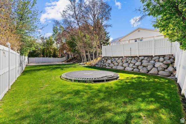 view of yard with a trampoline and a fenced backyard