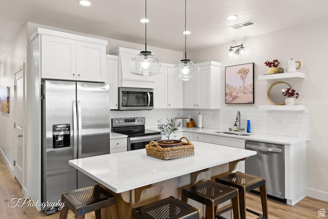 kitchen featuring a sink, a kitchen bar, visible vents, and appliances with stainless steel finishes
