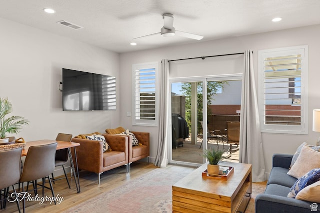 living area with light wood-style flooring, a ceiling fan, visible vents, and recessed lighting