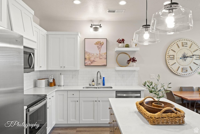 kitchen with a sink, stainless steel appliances, white cabinets, light countertops, and decorative backsplash
