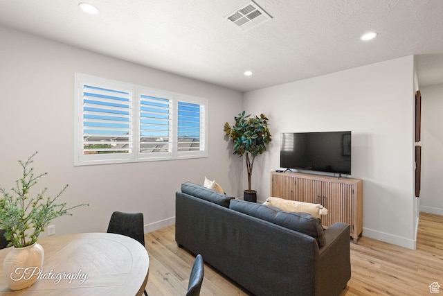 living area featuring light wood-style floors, visible vents, baseboards, and recessed lighting