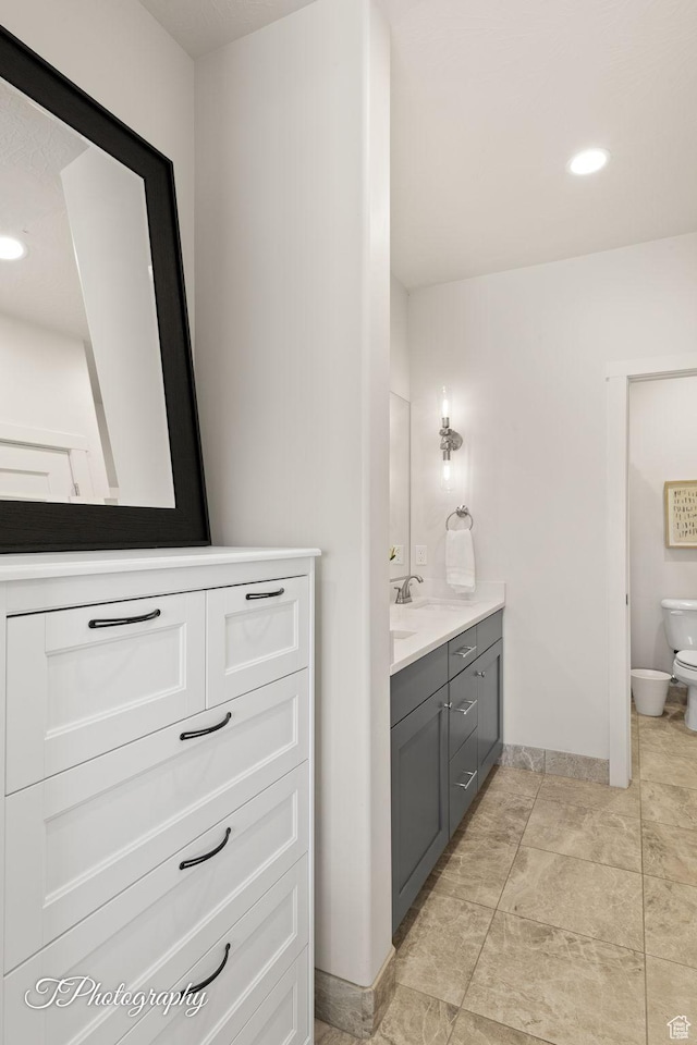 full bathroom with toilet, baseboards, vanity, and recessed lighting