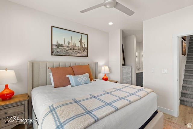 bedroom with a walk in closet, light wood-style floors, baseboards, ensuite bath, and recessed lighting