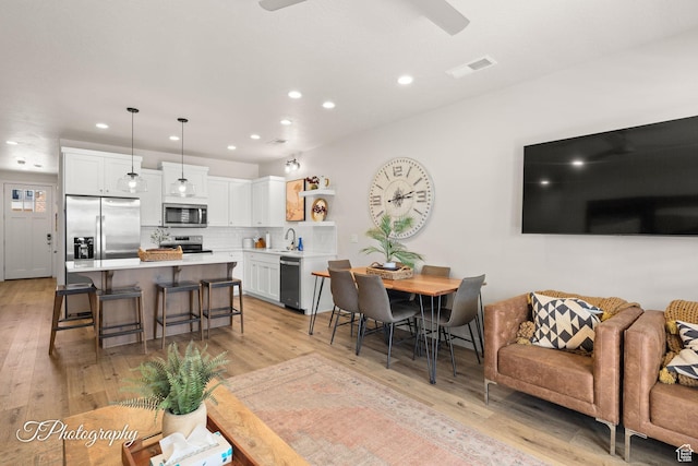 living room featuring a ceiling fan, recessed lighting, light wood finished floors, and visible vents