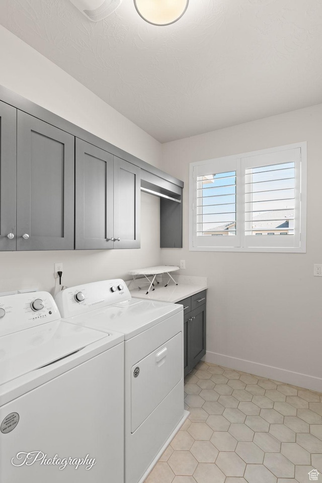 clothes washing area with separate washer and dryer, cabinet space, and baseboards