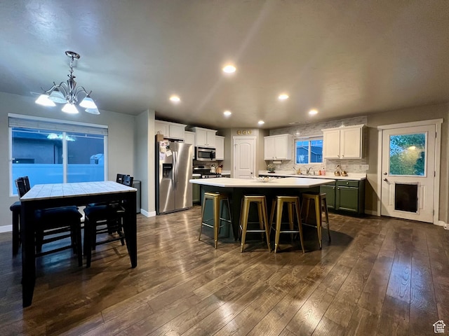 642 W Mulberry St, Stansbury Park, UT 84074 - kitchen featuring a kitchen island, stainless steel appliances, dark wood-type flooring, light countertops, and a chandelier