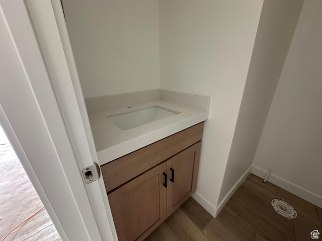 bathroom with baseboards, wood finished floors, and vanity