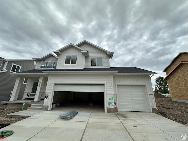 traditional home with concrete driveway, board and batten siding, covered porch, and an attached garage