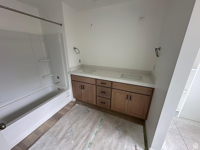 full bath with a sink,  shower combination, double vanity, and baseboards