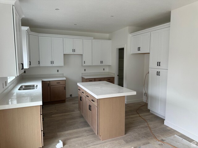 kitchen with light wood-type flooring, a center island, and white cabinetry