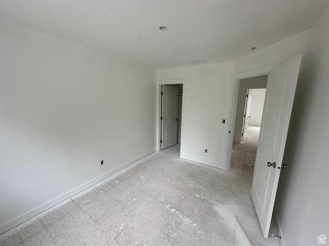 unfurnished bedroom featuring baseboards, visible vents, and a textured ceiling
