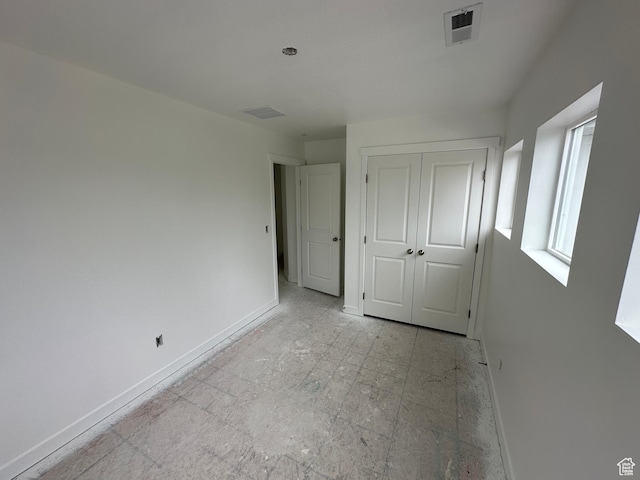 unfurnished bedroom featuring baseboards, a closet, and visible vents