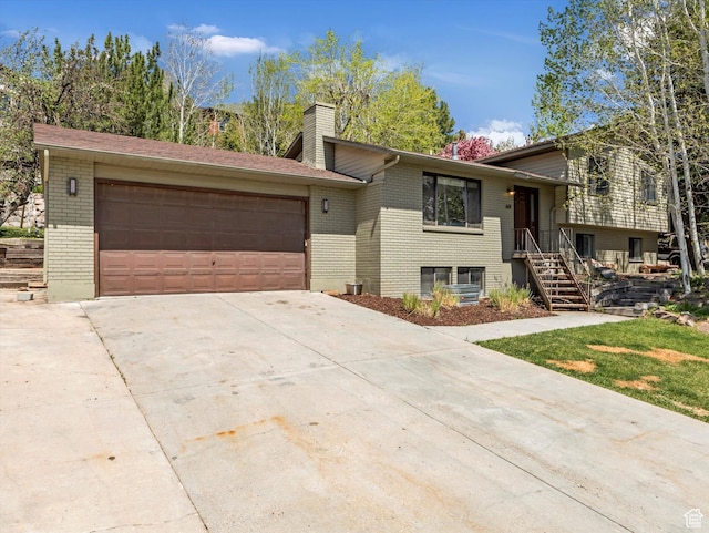 view of front of property featuring a chimney, brick siding, an attached garage, and concrete driveway