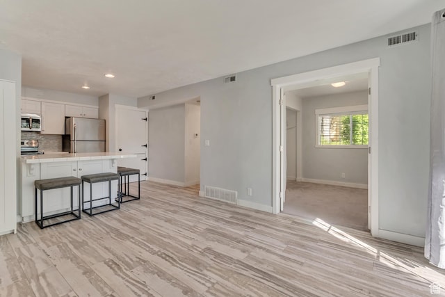 kitchen with a kitchen bar, stainless steel appliances, tile countertops, and visible vents