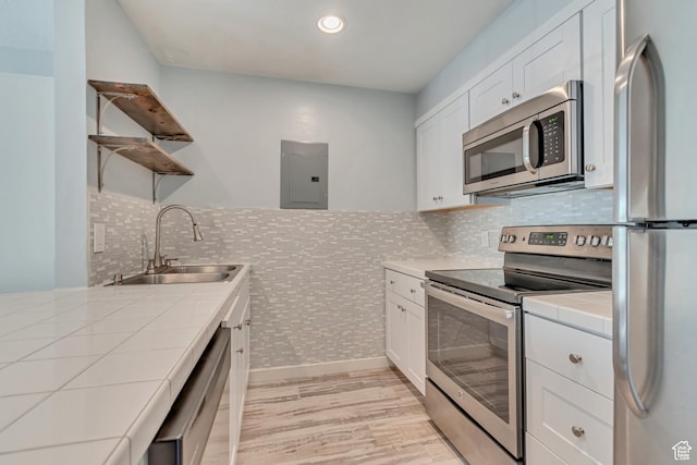 kitchen with electric panel, a sink, stainless steel appliances, open shelves, and tile countertops
