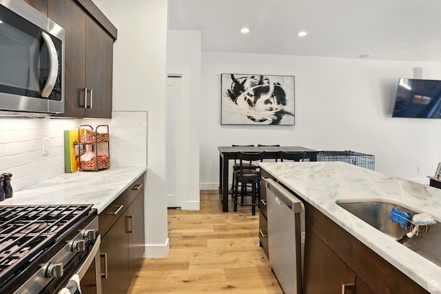 2237 N 450 W, Layton, UT 84041 - kitchen featuring dark brown cabinetry, light wood-style floors, stainless steel appliances, and decorative backsplash