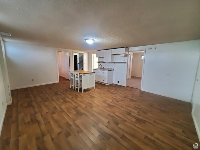 350 N 3rd St, Montpelier, ID 83254 - kitchen with white cabinets, dark wood-style flooring, open floor plan, a textured ceiling, and a kitchen breakfast bar