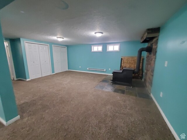 350 N 3rd St, Montpelier, ID 83254 - unfurnished room featuring a wood stove, a baseboard heating unit, carpet floors, baseboards, and a textured ceiling