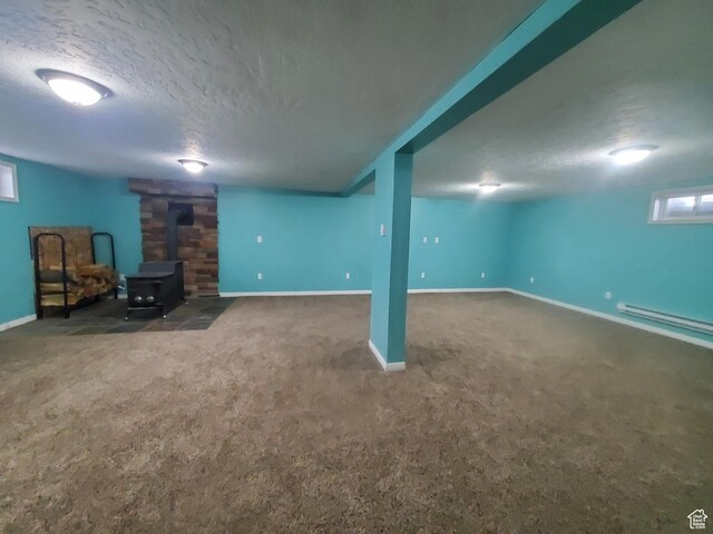 350 N 3rd St, Montpelier, ID 83254 - below grade area featuring a wood stove, a textured ceiling, carpet, a baseboard radiator, and baseboards