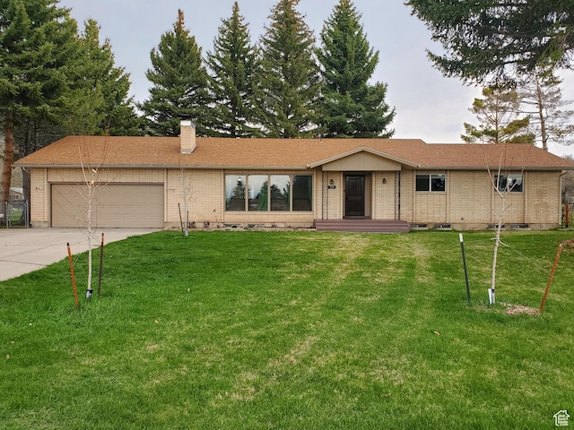 ranch-style house with a chimney, driveway, brick siding, an attached garage, and a front yard
