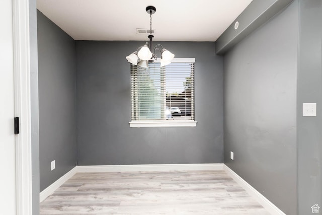 unfurnished room featuring baseboards, a chandelier, wood finished floors, and visible vents