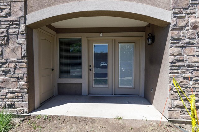 doorway to property with a patio area, stucco siding, and stone siding