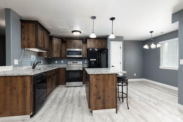 kitchen featuring a sink, light wood finished floors, baseboards, and black appliances