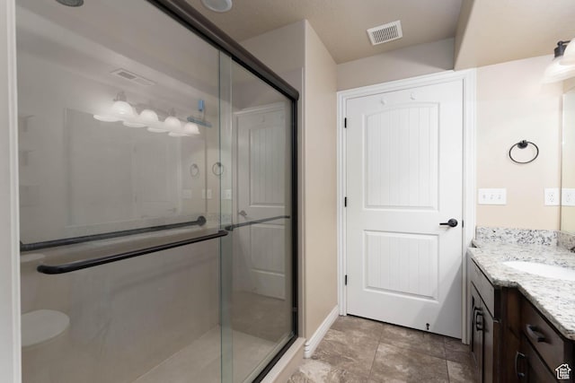 full bathroom featuring vanity, a shower stall, and visible vents